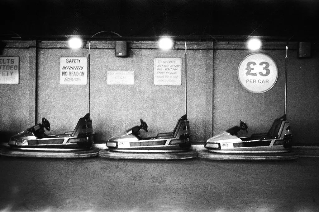 DragonFilm NO II Vintage black and white photo of bumper cars with price sign at a fairground.